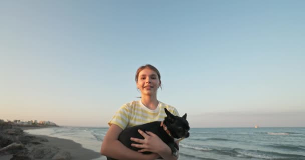 Een tienermeisje met een hond wacht op vertrek op het vliegveld. Een meisje met een huisdier in haar handen en een vliegtuig dat op de achtergrond landt. Toerisme vertrek voor vakantie samen met het gezin.  - Video