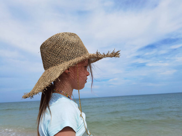 portrait of cute kid girl in straw hat on beach on sunny summer day - Foto, imagen