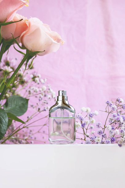 Parfümglasflasche mit Blumen herum. Minimales Konzept. - Foto, Bild