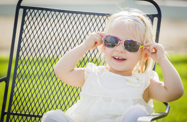 Leuke speelse babymeisje dragen van een zonnebril buiten in het Park - Foto, afbeelding