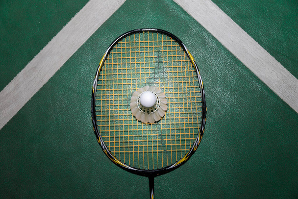 Vista superior de bádminton blanco Shuttlecock y raqueta en piso de madera. - Foto, imagen