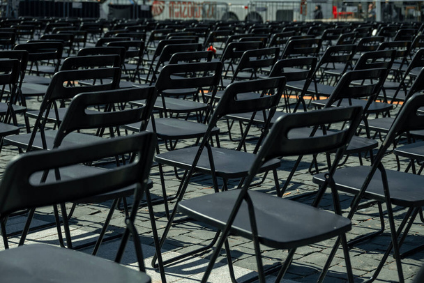 Rzędy czarnych plastikowych krzeseł na zewnątrz. Letni koncert plenerowy. Wysokiej jakości zdjęcie - Zdjęcie, obraz