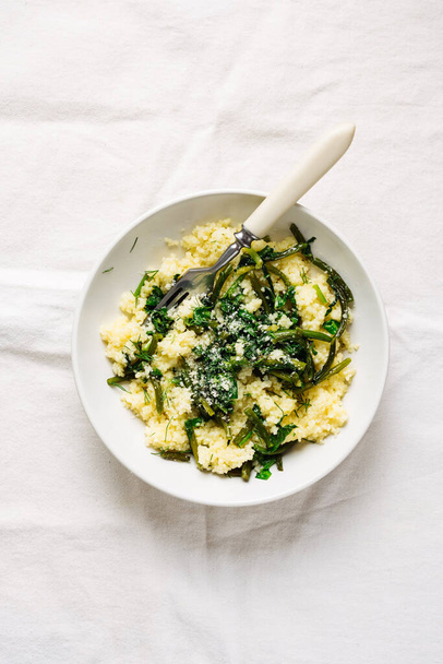 Couscous with garlic arrows and spinach, top view. Vegan cuisine. - Fotó, kép