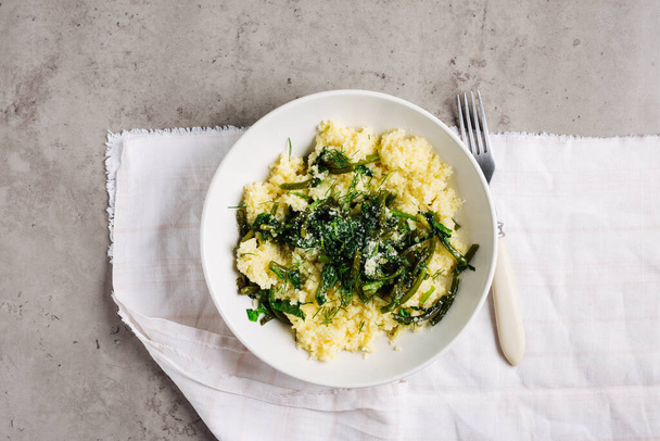 Couscous with garlic arrows and spinach, top view. Vegan cuisine. - Fotó, kép