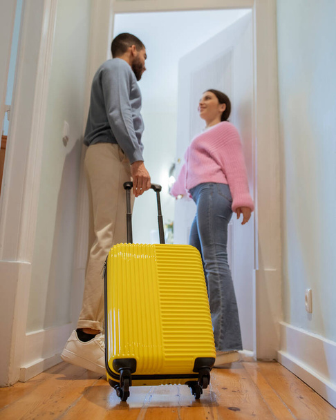 Hotelli Majoitus. Monikulttuurinen turistit Pariskunta keltainen matkalaukku Entering niiden Suite, seisoo oviaukossa sisätiloissa. Täysi pituus, pystysuora laukaus. Valikoiva keskittyä matkatavaroiden laukku - Valokuva, kuva