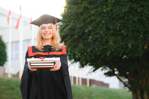 A young female graduate against the background of university - Zdjęcie, obraz