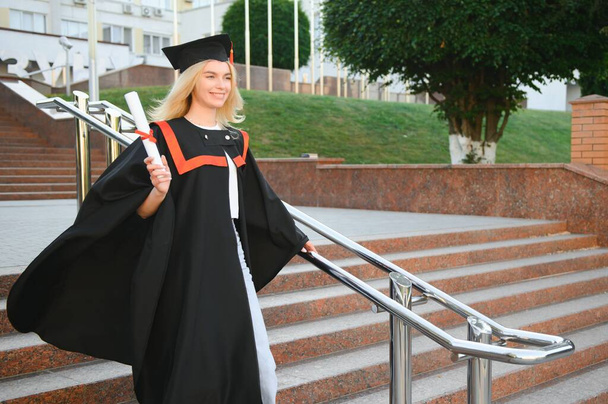 A young female graduate against the background of university - Zdjęcie, obraz