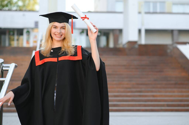 A young female graduate against the background of university - Fotó, kép