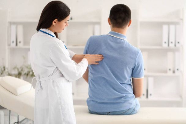 Female doctor checking posture of young man in clinic - Foto, Imagem