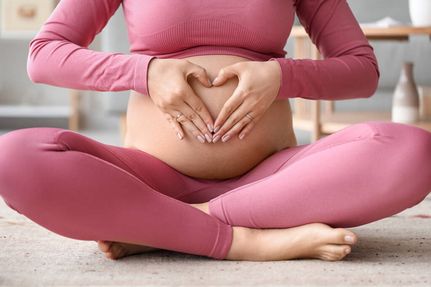 Sporty pregnant woman sitting at home, closeup - Foto, afbeelding
