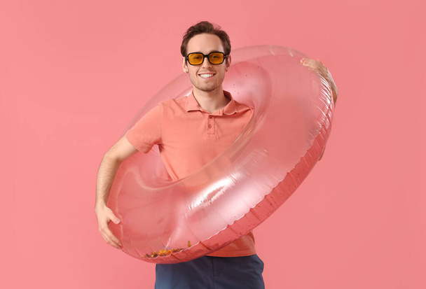 Young man with inflatable ring on pink background - Foto, immagini