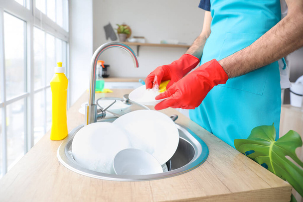 Junger Mann spült Geschirr in Küche - Foto, Bild