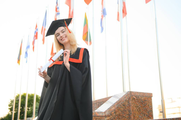 Young woman with beautiful smile in graduation gown. The concept of international education - Fotografie, Obrázek