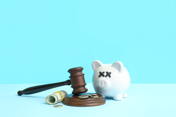 Piggy bank with judge gavel and money on blue background. Bankruptcy concept - Zdjęcie, obraz