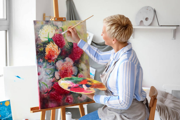 Mature female artist painting picture in  workshop - Photo, Image