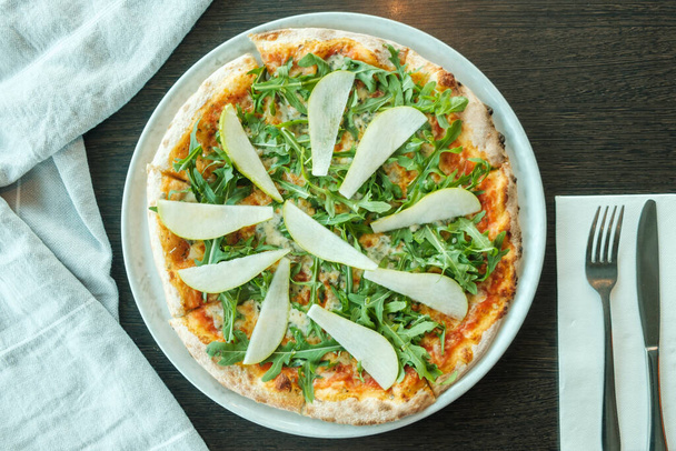 pizza with rocket and pear on a wooden table, close up  - Photo, image