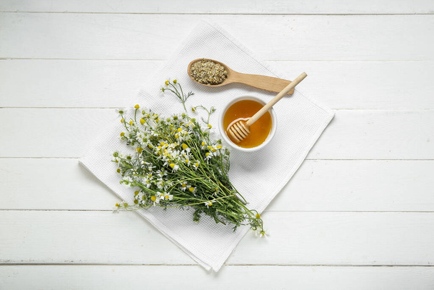 Ciotola di miele, fiori di camomilla freschi e secchi su fondo di legno chiaro - Foto, immagini