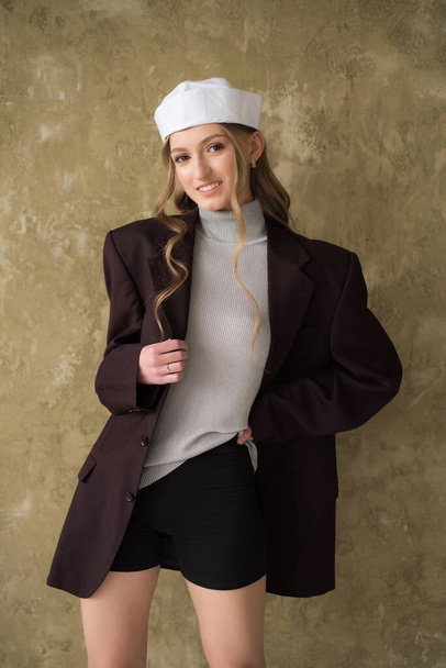 young girl in beige coat and hat on a beige background  - Fotografie, Obrázek