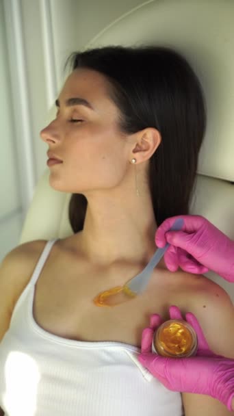 4kビデオ美容師は、皮膚の更新の自然なプロセスを刺激し、弾力性を復元するために体に金のリフティングマスクを適用します - 映像、動画