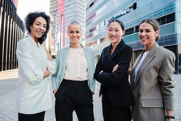 Eine Gruppe gut aussehender Geschäftsfrauen steht am Arbeitsplatz und posiert mit erfolgreicher Miene für das Porträt. Ermächtigte und stolze weibliche Führungskolleginnen blicken mit formellen Anzügen in die Kamera - Foto, Bild