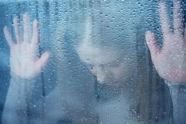 mujer joven melancólica y triste en la ventana bajo la lluvia
 - Foto, imagen