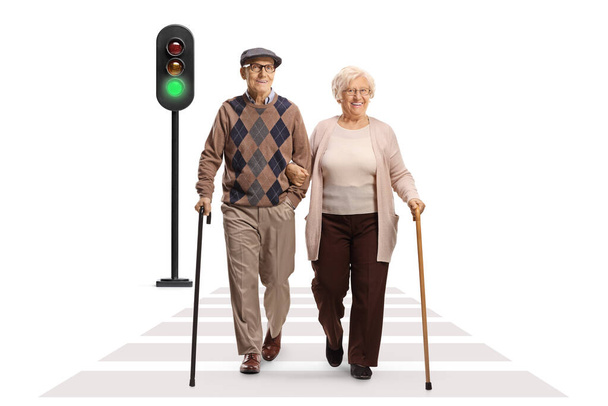 Full length portrait of an elderly man and woman walking with canes at pedestrian crossing isolated on white background - Zdjęcie, obraz