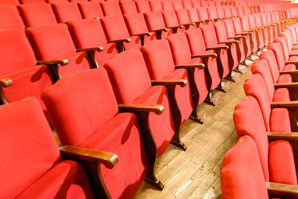 Fila di sedili rossi in un teatro con vecchio pavimento in legno. - Foto, immagini