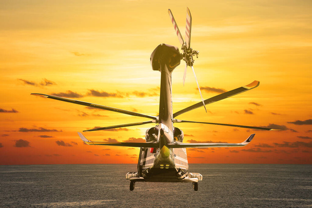 Helikopter repül az égbe naplementével vagy napkeltével. A repülés az égen, és az utazás más helyre. - Fotó, kép