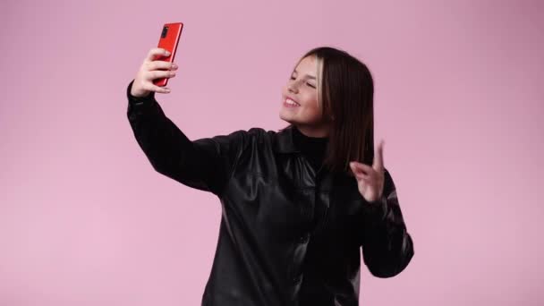 4k video yksi tyttö, joka ottaa selfietä puhelimellaan vaaleanpunainen tausta. Tunteiden käsite. - Materiaali, video