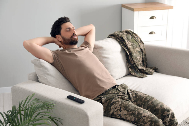Soldier napping on soft sofa in living room. Military service - Foto, Bild