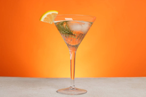 Martini glass of refreshing cocktail with lemon slice and rosemary on light grey table - Valokuva, kuva
