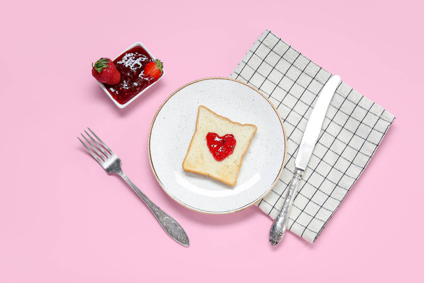 Talerz z tostem, słodki dżem truskawkowy i sztućce na różowym tle - Zdjęcie, obraz