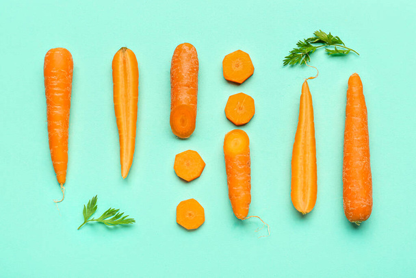 Zanahorias frescas y rodajas sobre fondo turquesa - Foto, imagen