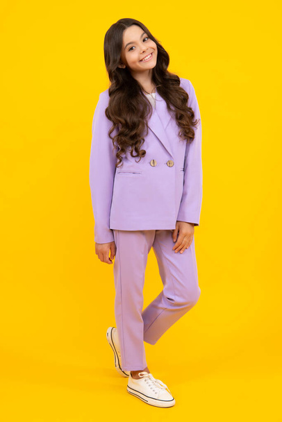 Full length of cheerful teenager child girl wearing comfy trendy fashion clothes, isolated over yellow background. Happy teenager, positive and smiling emotions of teen girl - Zdjęcie, obraz