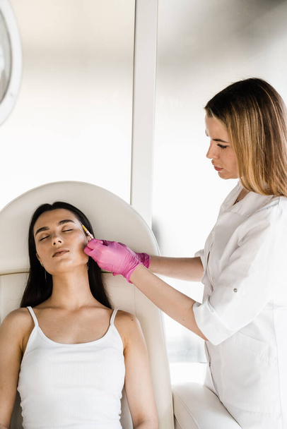 Cosmetologist injecting facial biorevitalization for moisturizing effect. Facial biorevitalization for increasing skin tone, reducing wrinkles, and strengthening oval of the face - Photo, image