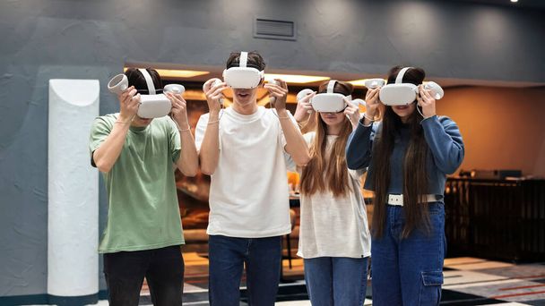 Arenada VR kulaklık ve joysticklerle oynayan bir grup arkadaş. - Fotoğraf, Görsel
