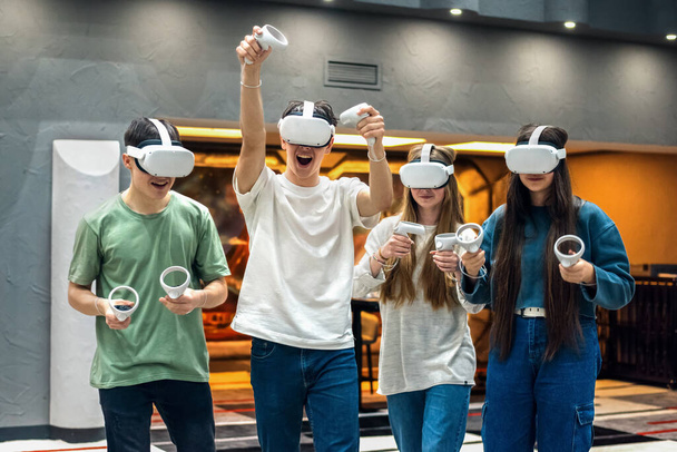 Eine Gruppe von Freunden spielt mit VR-Headset und Joysticks in der Arena - Foto, Bild