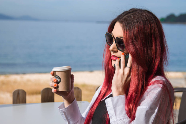 nő beszél a telefonján a szabadtéri kávézóban, és kávézás - Fotó, kép