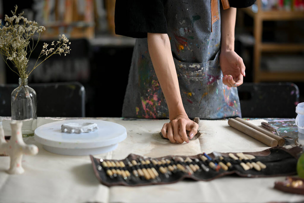 Zbliżenie obrazu artysty garncarza ugniatającego surową glinę na stole w pracowni garncarskiej. rzemiosło, warsztat garncarski, ceramika, rzeźba - Zdjęcie, obraz