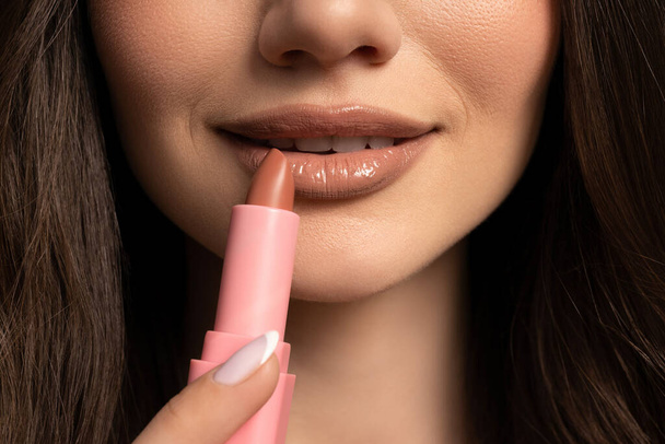 Das Mädchen bemalt ihre Lippen mit lippensticknude Farbe - Foto, Bild