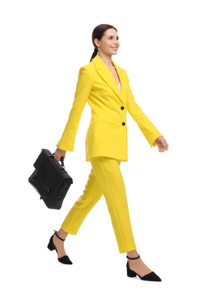 Beautiful businesswoman in yellow suit with briefcase walking on white background - Foto, Bild