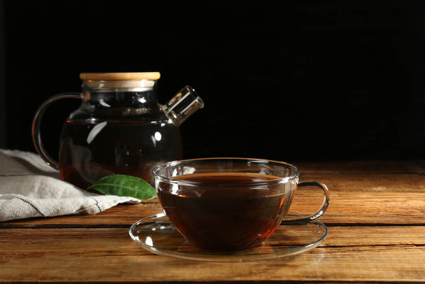 Cup of aromatic tea and teapot on wooden table - Fotografie, Obrázek