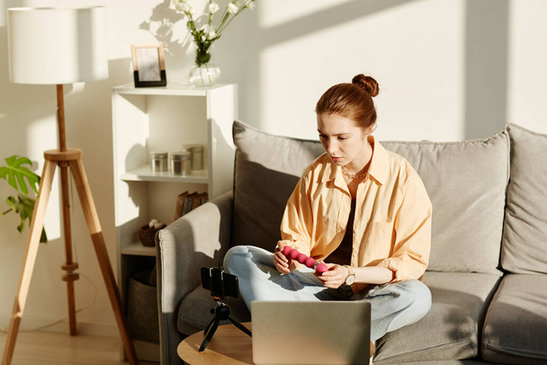 Retrato mínimo de mulher jovem filmando vídeo educação sexual em casa e segurando vibrador rosa, espaço de cópia - Foto, Imagem