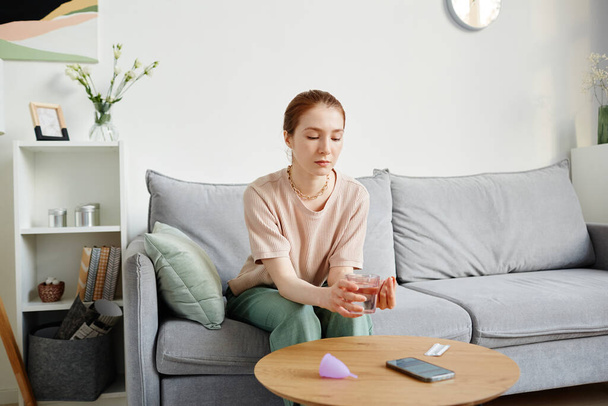 Portrait of young woman taking medication while suffering from period pains, copy space - Foto, afbeelding