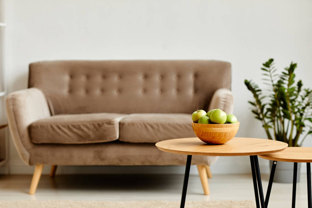 Background image of green apples bowl on wooden table in minimal living room interior with cozy couch, copy space - Photo, Image