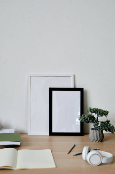 Imagen de fondo vertical del lugar de trabajo simple de los estudiantes con marcos en blanco y árbol de bonsái en el escritorio, espacio de copia - Foto, Imagen