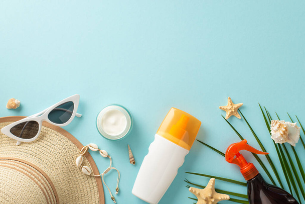 Healthy summer tan concept. Top view photo of empty space above sunscreen bottles, tubes, sprays and cream, shells and sunglasses with sunhat on blue isolated background with copy-space - Φωτογραφία, εικόνα