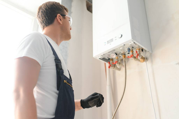 Professional plumber checking a boiler and pipes, boiler service concept. - Φωτογραφία, εικόνα