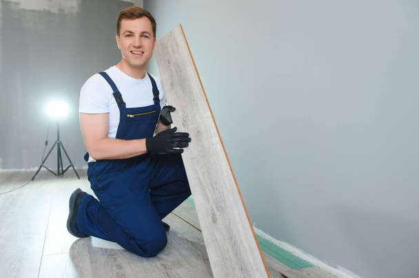 Repairman laying laminate flooring at home. - Foto, Bild