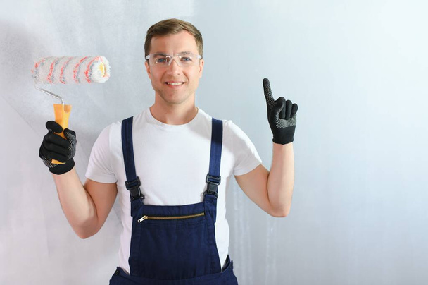 repair, building and home concept - close up of male in gloves holding painting roller. - Foto, Imagen
